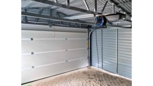 5×5m große Delux-Mobilgarage mit Satteldach, in Dunkelgrün, mit Sektionaltor, Seitentür, Dachrinne, Verkleidungen, verzinkter Rahmenkonstruktion und horizontaler Blechverkleidung