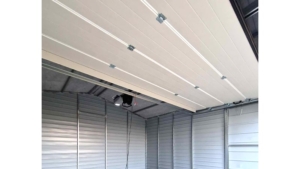 5×5m große Delux-Mobilgarage mit Satteldach, in Dunkelgrün, mit Sektionaltor, Seitentür, Dachrinne, Verkleidungen, verzinkter Rahmenkonstruktion und horizontaler Blechverkleidung
