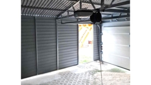 5×5m große Delux-Mobilgarage mit Satteldach, in Dunkelgrün, mit Sektionaltor, Seitentür, Dachrinne, Verkleidungen, verzinkter Rahmenkonstruktion und horizontaler Blechverkleidung