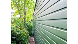 5×5m große Delux-Mobilgarage mit Satteldach, in Dunkelgrün, mit Sektionaltor, Seitentür, Dachrinne, Verkleidungen, verzinkter Rahmenkonstruktion und horizontaler Blechverkleidung